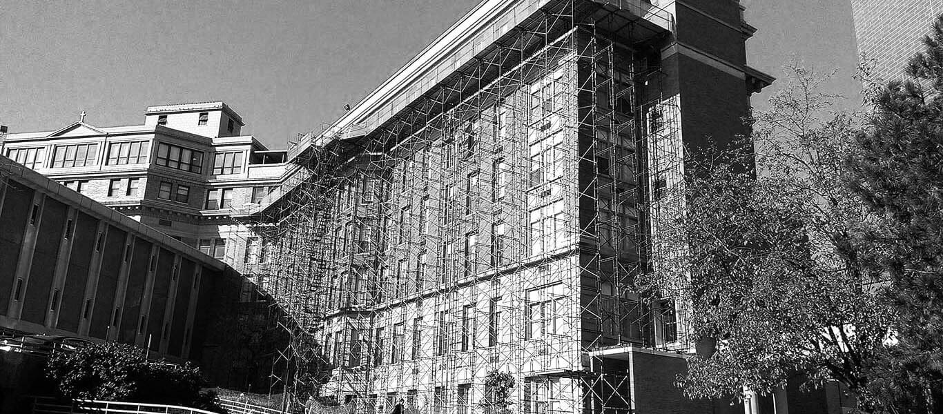 Large commercial building undergoing facade restoration with extensive metal scaffolding covering the brick and stone exterior walls in Cincinnati